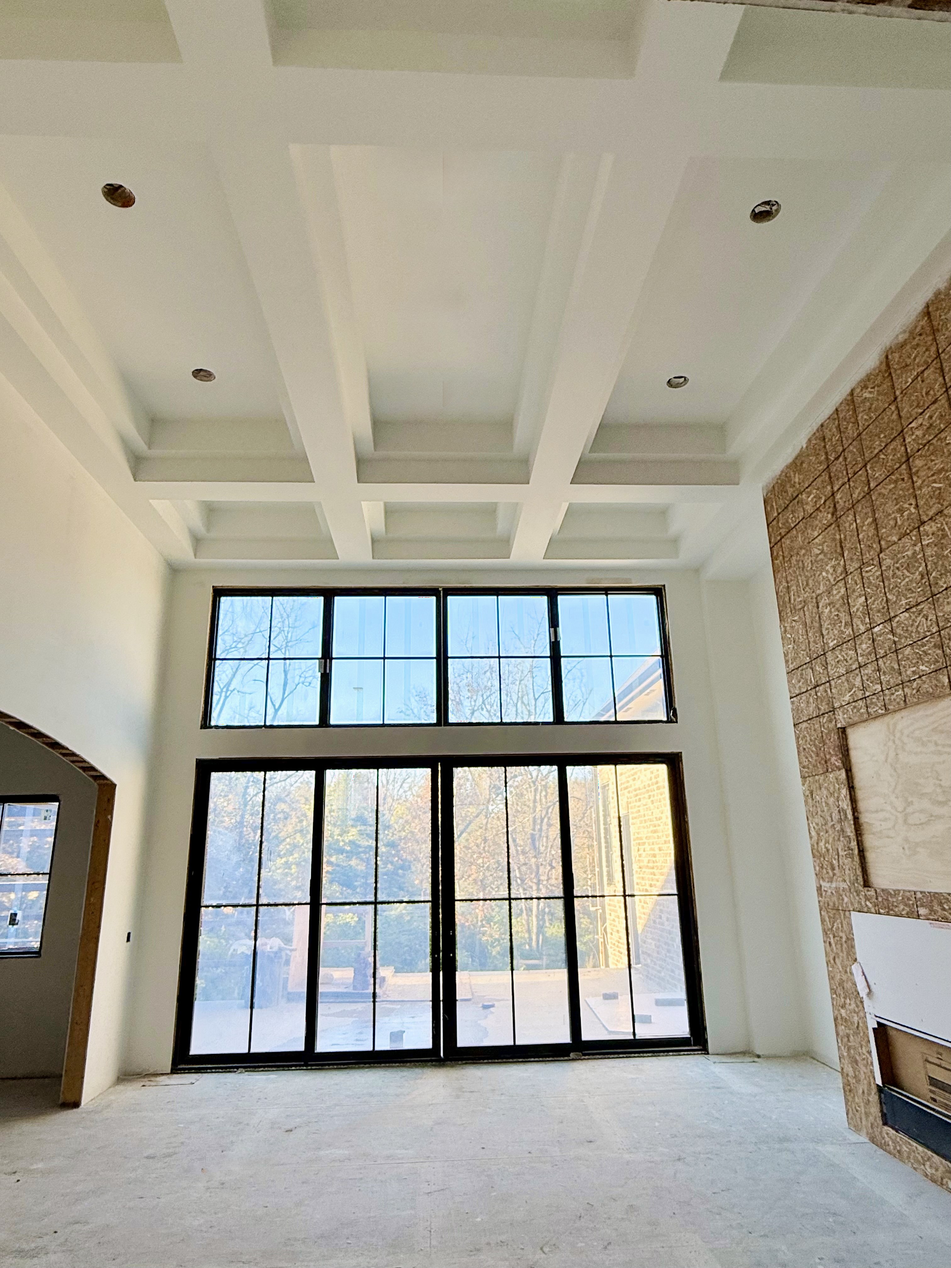 New build: two-story great room with a coffered ceiling above a wall of windows